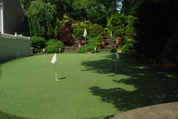 Huntsville Synthetic grass golf green with flags in a landscaped backyard